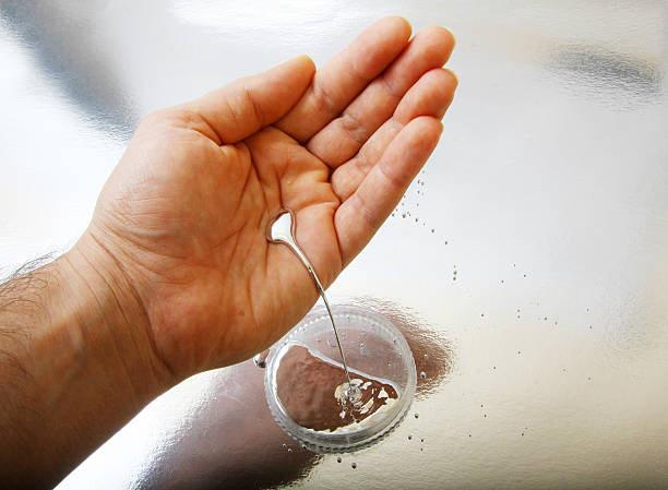 A hand holding a dropper, releasing a liquid containing heavy metals into a container.