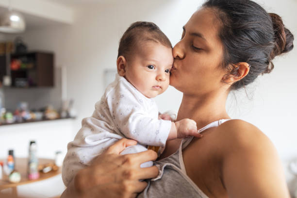 A mother lovingly kissing her baby on the forehead, symbolizing hope and joy in motherhood.