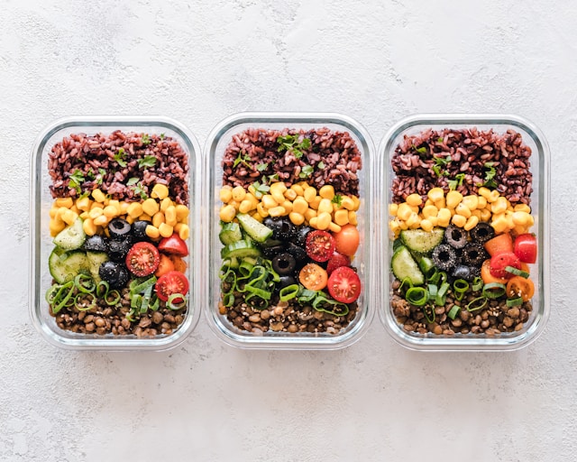 Three containers of colorful plant-based meals with a variety of legumes, grains, and vegetables.