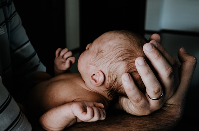 A newborn baby cradled in a parent's hands, highlighting the delicate and precious nature of new life.