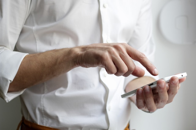 A person in a white shirt using a smartphone, highlighting modern technology use.