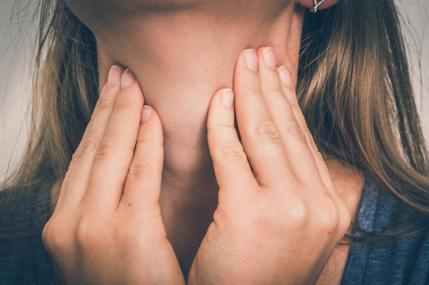 Close-up of a woman gently touching her throat, a common gesture for checking thyroid gland health.